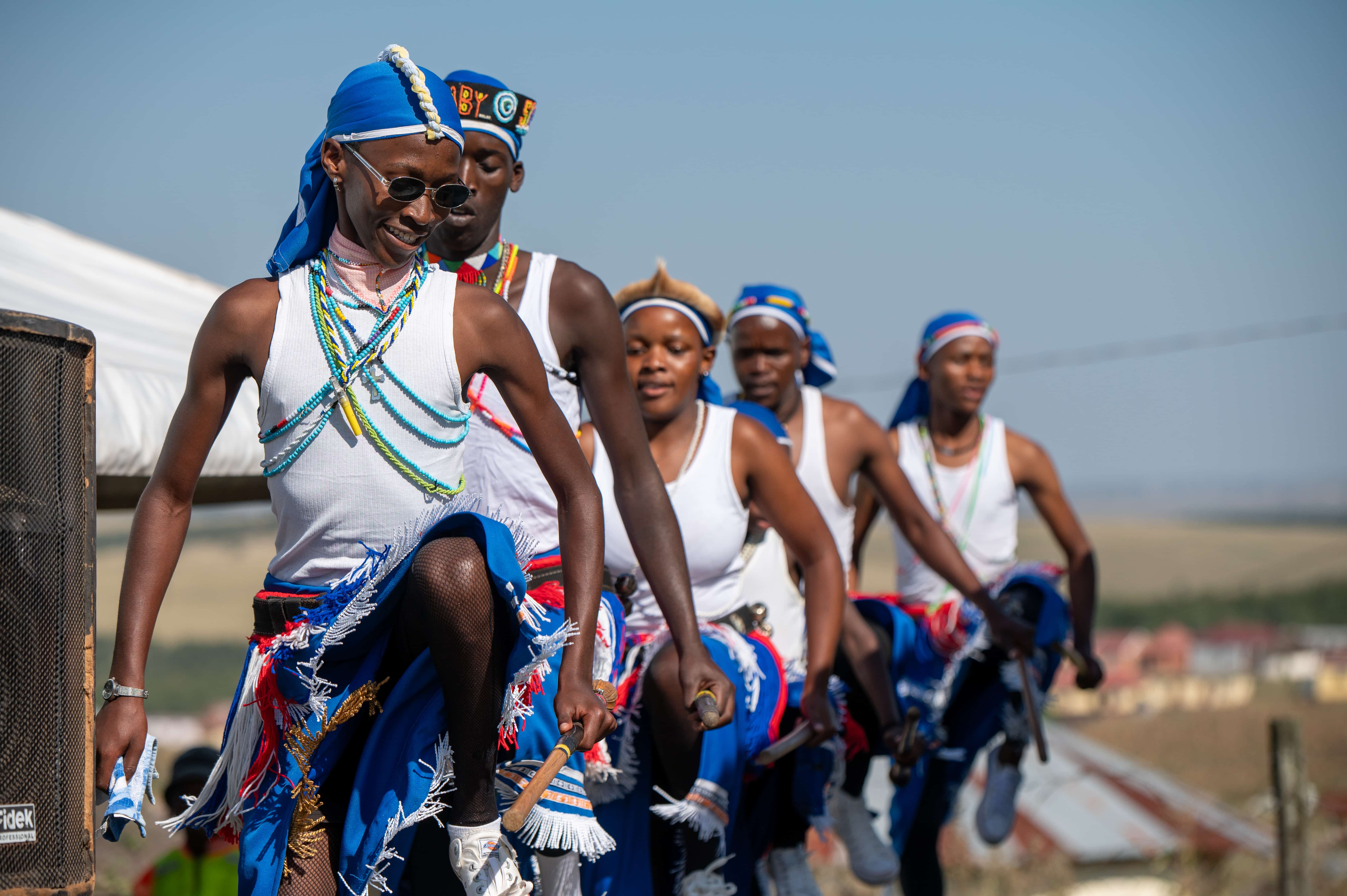 Young performers in traditional Xhosa dress dancing at a community event